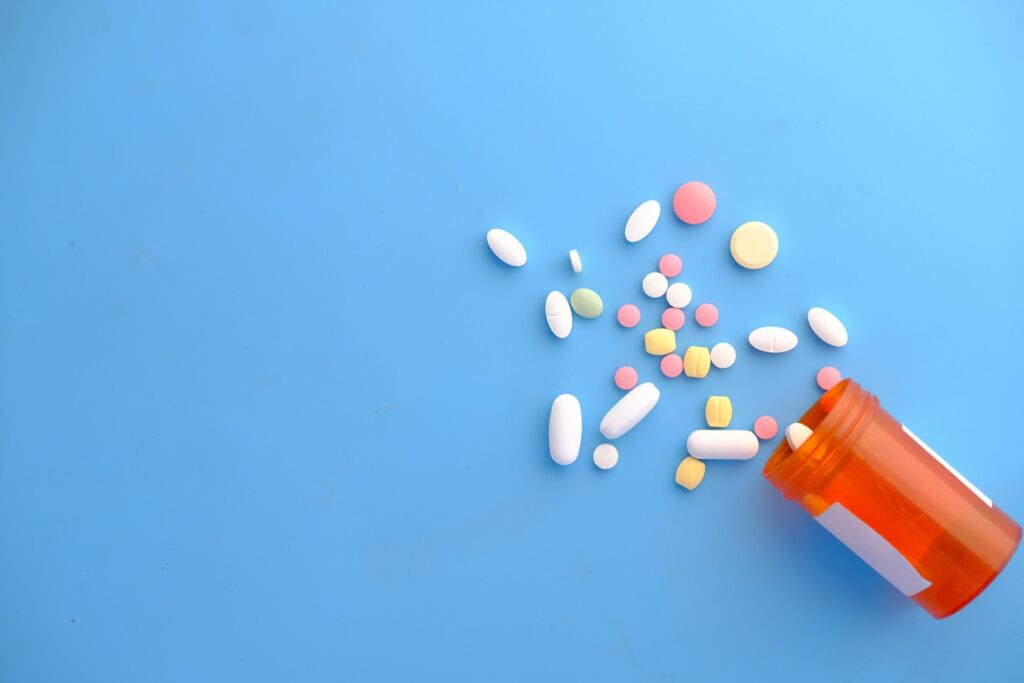 colorful pills spilling from orange bottle